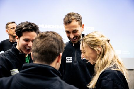 Viert junge Menschen im Gespräch, eine weitere Person im Hintergrund