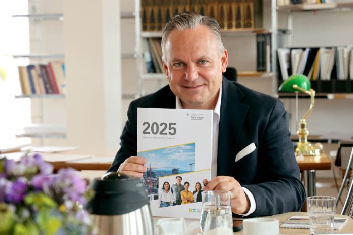Wirtschaftsreferent Scharpf am Schreibtisch zeigt Jahreswirtschaftsbericht München 2025