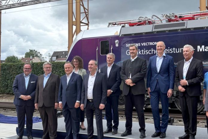 Gäste zur Eröffnung bei Siemens Mobility in Allach, dahinter Lok