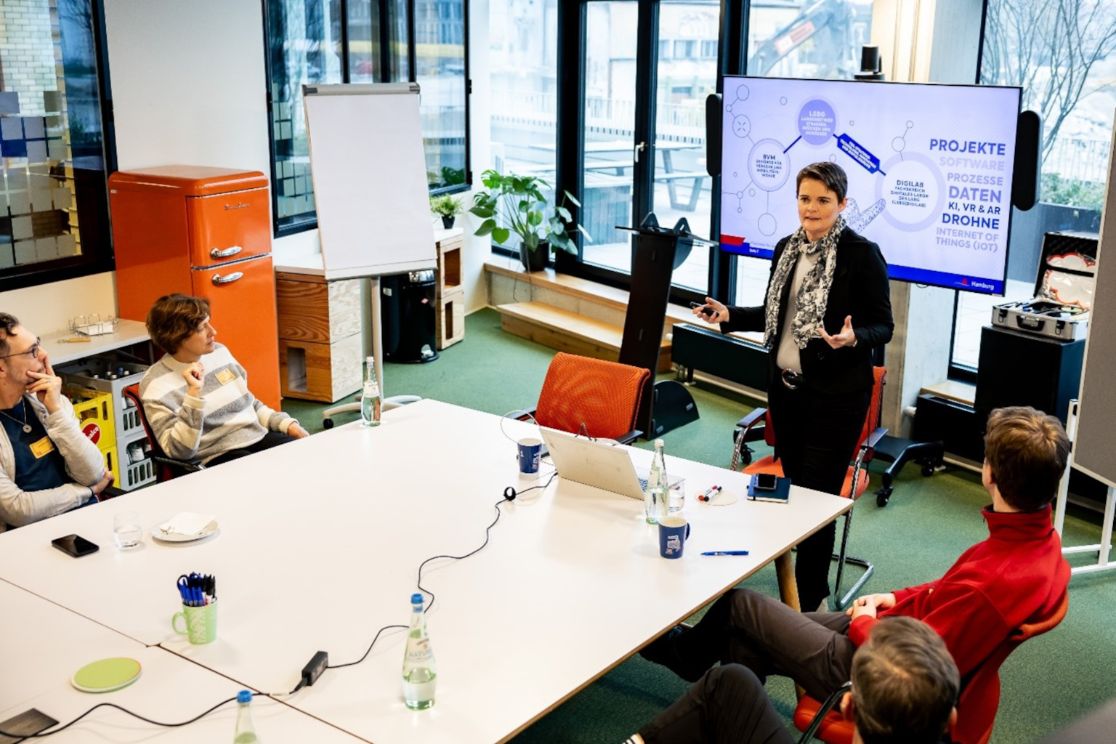 Workshop mit Teilnehmern an einem Gruppentisch und Referentin
