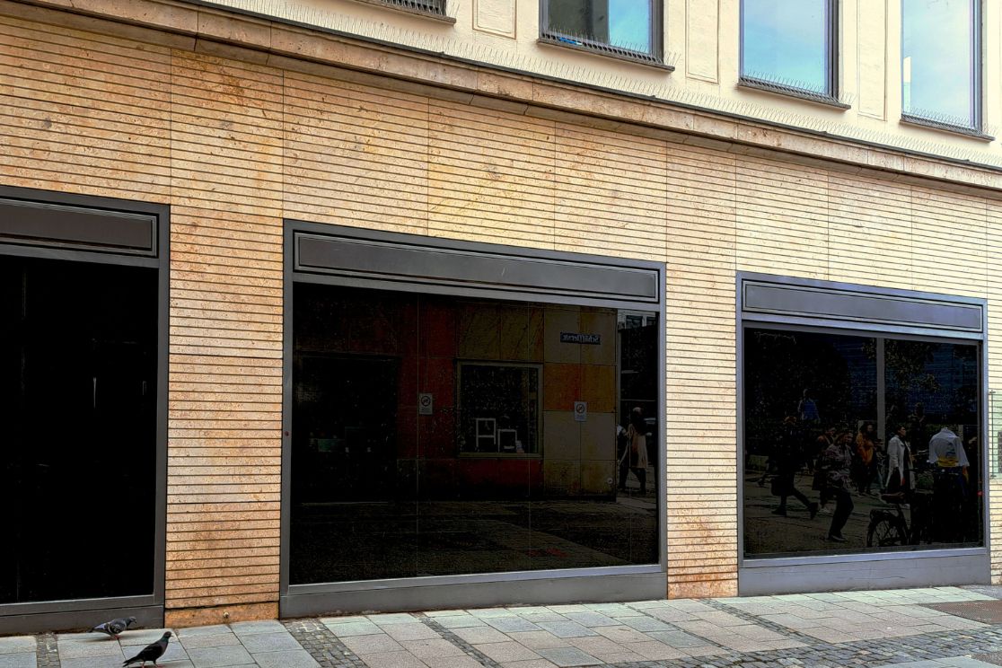 Drei schwarz verspiegelte Schaufenster in einer holzverkleideten Fassade