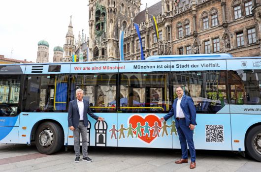 OB Dieter Reiter und MVG-Geschäftsführer Ingo Wortmann und ein MVG-Bus mit Großaufklebern "Sei ein Mensch | Wir alle sind München. München ist eine Stadt der Vielfalt" auf dem Marienplatz.