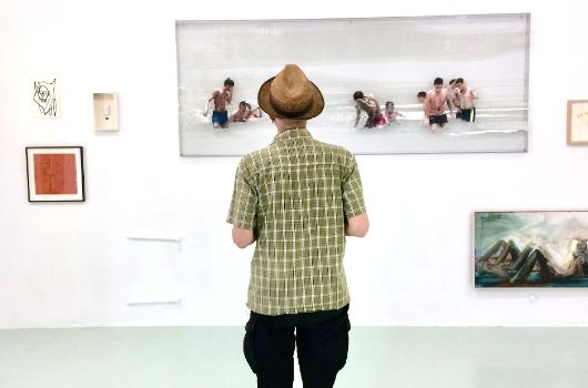 Ein Mann betrachtet Kunstwerke an der Wand in der Artothek.