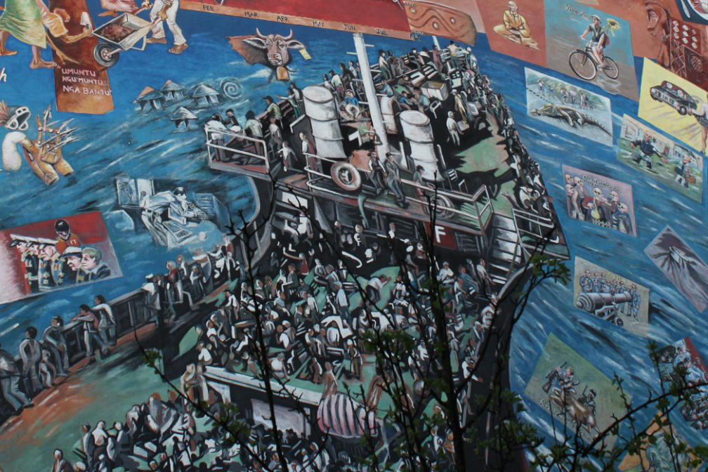 Wandmalerei auf dem EineWeltHaus in München mit Fluchtsituation auf einem Schiff.