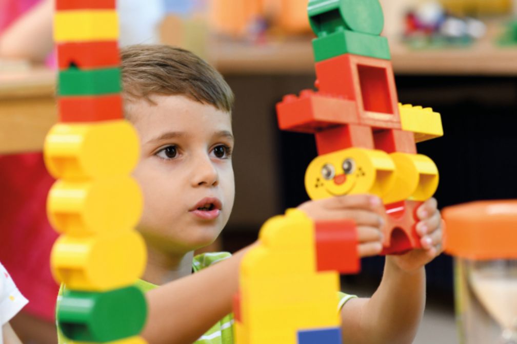 Braunhaariges Kleinkind spielt mit Legobausteinen
