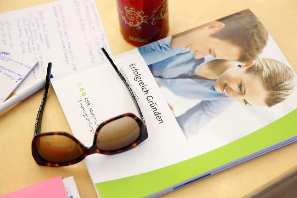 Broschüre des MEB zum Thema Unternehmensgründung, Sonnenbrille, Notizen auf einem Tisch