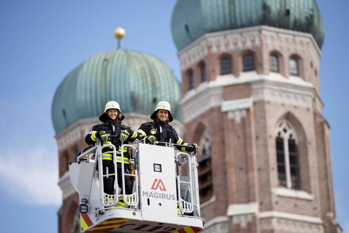 Zwei Brandmeister in Schutzausrüstung im Drehleiterkorb vor der Frauenkirche