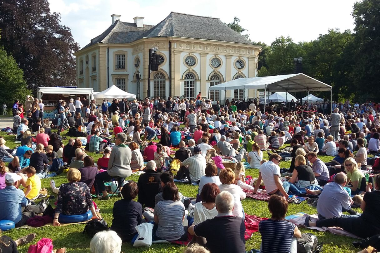 Blick auf die Badenburg mit Bühne und zahlreichen Zuschauern auf Picknickdecken.