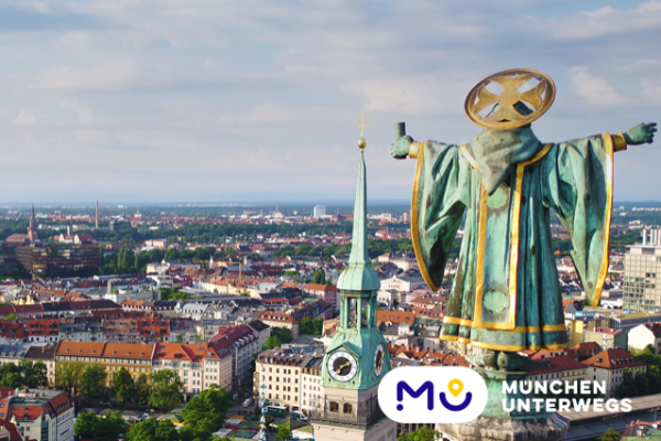 Blick auf die Stadt von Münchner-Kindl-Statue aus mit Logo von München Unterwegs