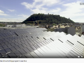 Screenshot aus dem ÖKOPROFIT-Video des Umweltamtes Graz: Blick über eine Photovoltaikanlage und die Stadt Graz