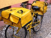 Gelbes Fahrrad der Deutschen Post auf Gehsteig.