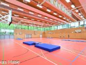 Dreifachsporthalle der Grundschule Infanteriestraße mit roter Decke und rotem Fußboden und blauen Matratzen