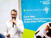 Munich Impact Incubator 2024 - Teilnehmer auf der Bühne mit Micro 