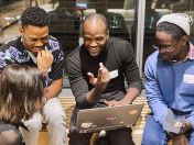 Vier Studierende mit Notebook im Gespräch