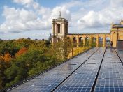 Blick auf die Solarpaneele auf dem Dach des Münchner Maximilianeums, dahinter die Gebäudefront und Bäume an der Isar 
