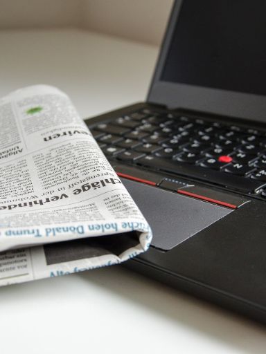 Eine Zeitung und ein aufgeklappter Laptop