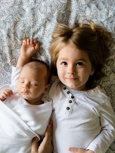 Kleines Mädchen und Baby auf Decke
