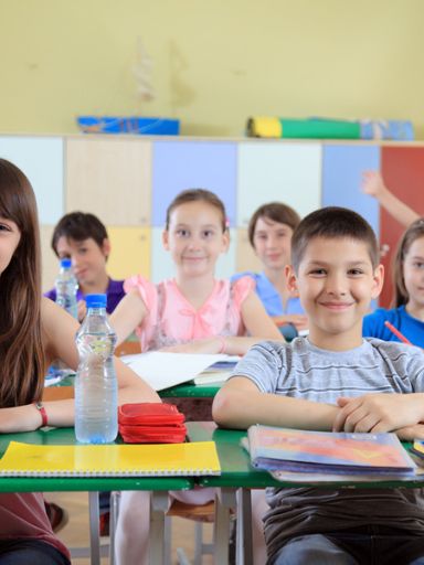 Grundschulkinder sitzen in der Klasse an Ihren Bänken