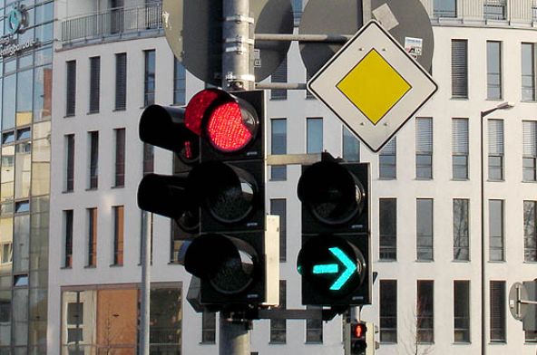 Ampel an Kreuzung zeigt grün leuchtenden Rechtspfeil und rot für die anderen Richtungen