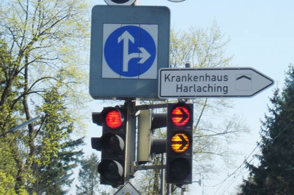 Wechselverkehrszeichen an einer Ampel zeigt weißen Geradeaus-Rechts-Pfeil an
