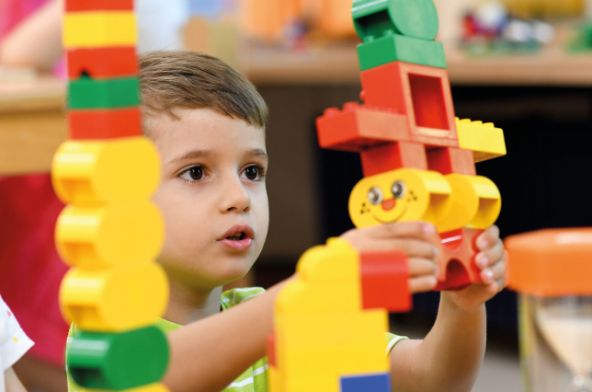 Braunhaariges Kleinkind spielt mit Legobausteinen