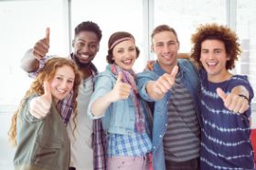 Eine Gruppe von Jugendlichen lachen und strecken den Daumen hoch