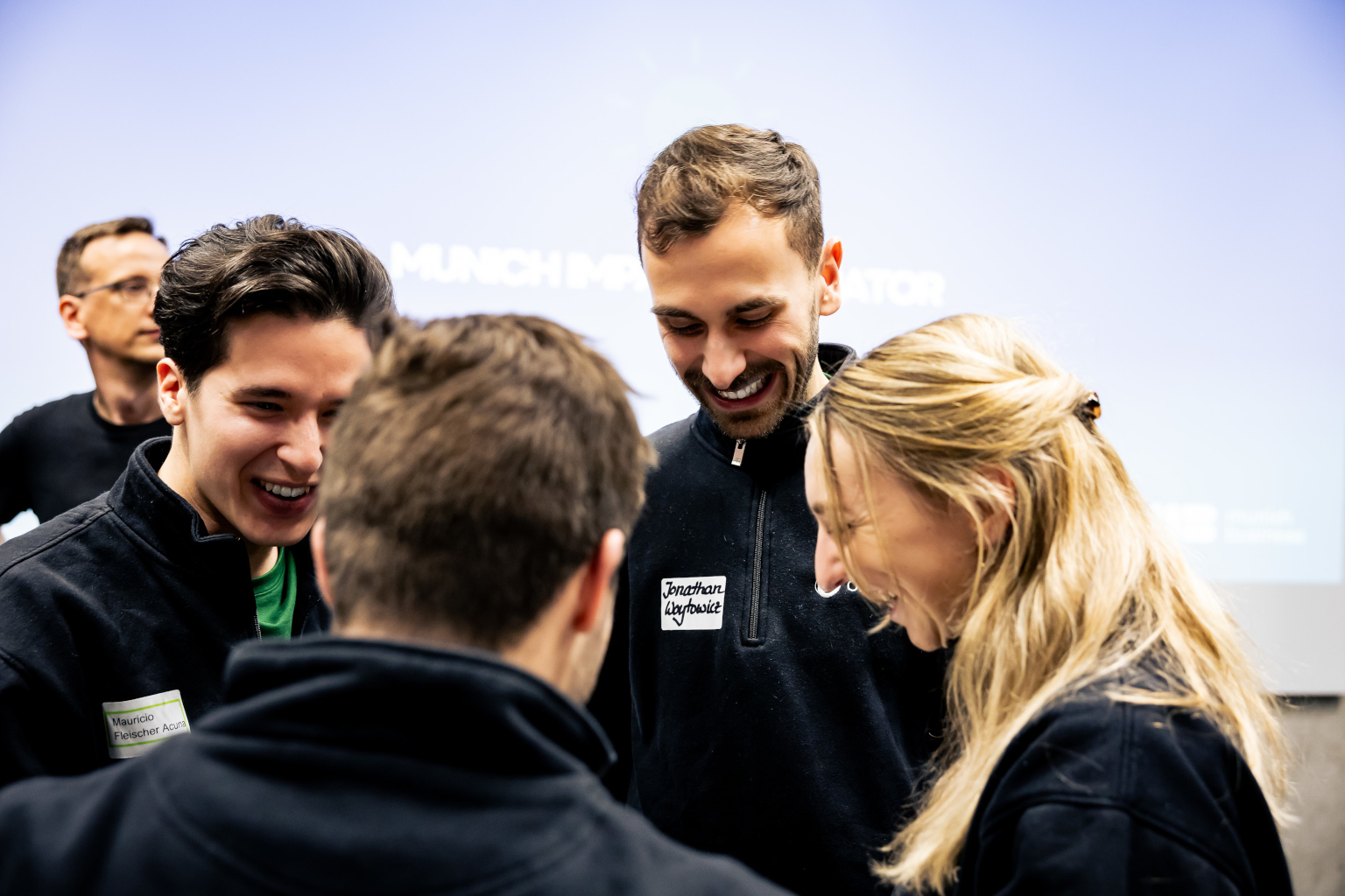 Viert junge Menschen im Gespräch, eine weitere Person im Hintergrund